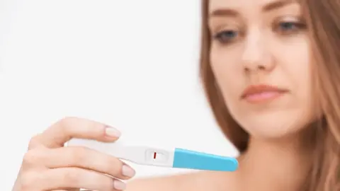 Getty Images woman holding pregnancy test with negative result