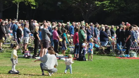 People standing watching a big screen in Guernsey's Saumarez Park showing the state funeral of Queen Elizabeth II