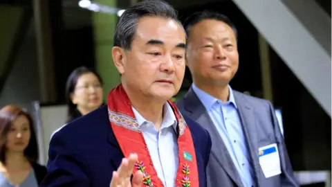 Reuters People"s Republic of China Foreign Minister Wang Yi gestures as he is escorted by Zhao Jianhua, Chinese ambassador to the Philippines, upon arrival at the international airport of Pasay to attend the 50th ASEAN Foreign Ministers meeting, metro Manila, Philippines August 5, 2017