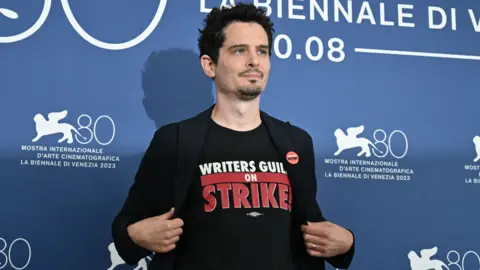 Getty Images US director and president of the jury Damien Chazelle wearing a tee-shirt in solidarity with Writers Guild on strike poses on August 30, 2023, during a photocall for the Jury of the 80th International Venice Film Festival at Venice Lido