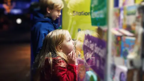 Getty Images Children look at toys in a shop window at Christmas