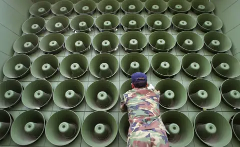 Getty Images Man standing in front of a speaker stack