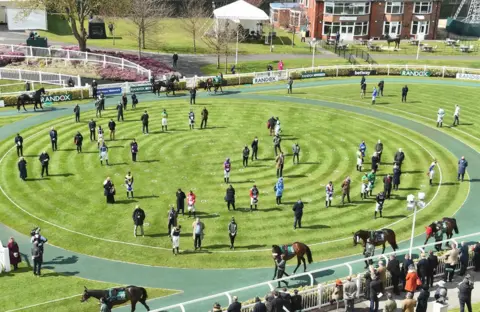 EPA Jockeys and trainers observe two minutes of silence to honour the memory of Prince Philip at the racecourse in Aintree, Britain, 10 April 2021, before the start of the races on Grand National Day at the Grand National Festival in Aintree.