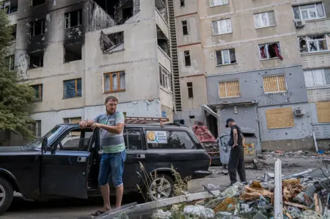 BBC Food delivery volunteer Leon Petrosyan smokes a cigarette. "The people here have nowhere else to go," he said. "They are trapped"