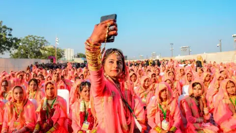 Getty Images A Muslim bride takes a selfie with her mobile phone as she participates in an 'All Religion Mass Wedding' ceremony at Sabarmati Riverfront in Ahmedabad on February 8, 2020