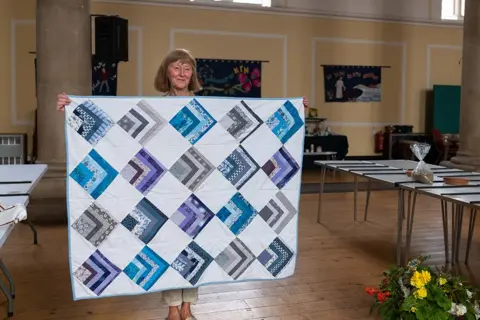 Jim Grover Elaine Andrews holding her patchwork quilt