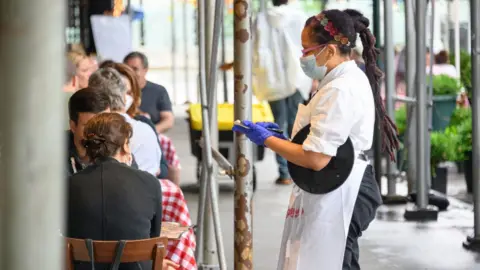 Getty Images A waitress serving customers at a New York City restaurant