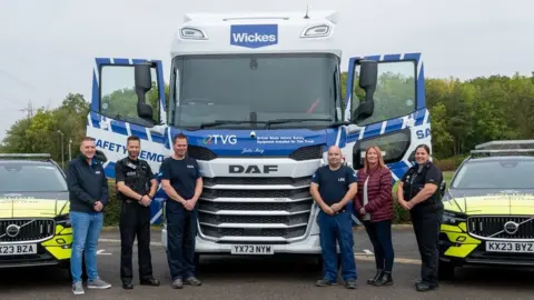 Northamptonshire Police Large blue and white lorry cab with "Julie May" on the front and six people standing in front of it