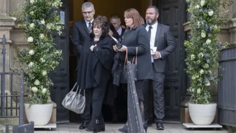 PA Media Partick Thistle chairwoman Jacqui Low (left) leads the mourners after the funeral service