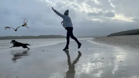 PA Media Woman with dog on beach in Padstow