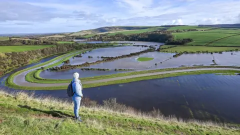 Simon Dack News / Alamy Stock Photo Flooded fields and farmland at Alfriston, East Sussex, by the River Cuckmere which burst its banks.