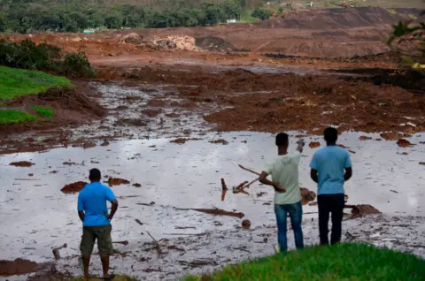 AFP/Getty Images People survey the damage after the dam burst in Brazil