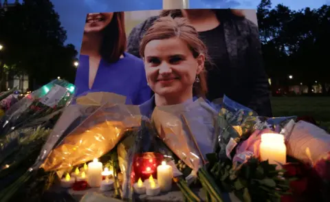 Getty Images Floral tributes and candles are placed by a picture of Labour MP Jo Cox at a vigil in Parliament square in London