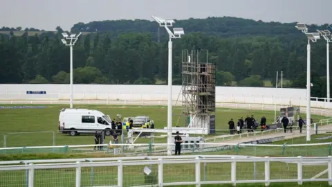 PA Media Police officers and other people on the track at a racecourse