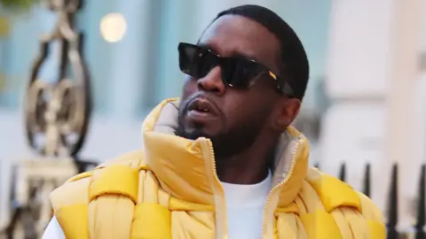 Sean Combs aka Diddy looks on wearing black sunglasses and yellow puffer jacket while out and about on November 10, 2023 in London, United Kingdom