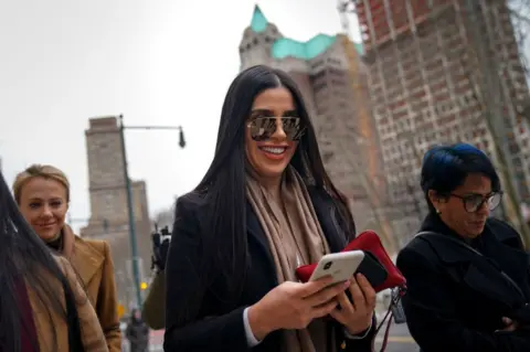 Getty Images Guzmán's wife, Emma Coronel Aispuro, walking outside with colleagues