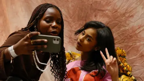 PHILL MAGAKOE/AFP Tyla (R) poses for a selfie with a fan (L).