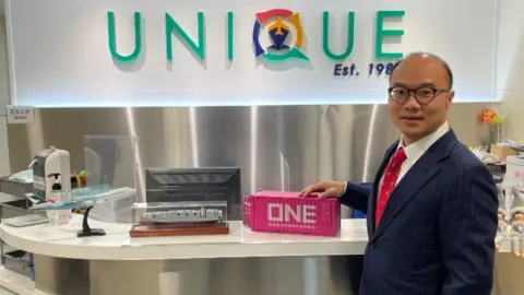 Unique Logistics International Hong Kong-based logistics specialist Patrick Lee holding a model shipping container