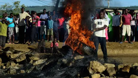 AFP flames shooting out of a tyre as a crowd looks on