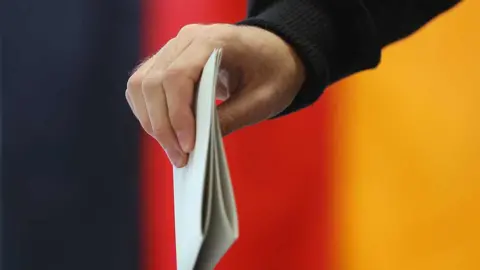 Hand holding ballot paper next to Germany flag