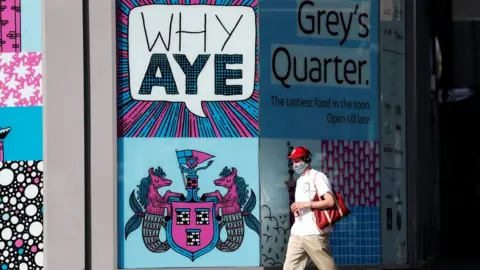 Reuters Man wearing a mask walking through the centre of Newcastle