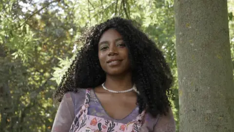 Dominique Palmer  Climate justice cctivist, Dominique Palmer standing underneath trees