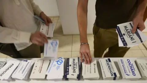 AFP French residents pick up their ballots before casting their vote in the French legislative elections at the French embassy in New Delhi on 4 June 2017