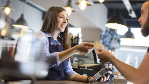 Getty Images Waitress accepting a customers' payment.