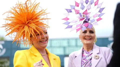 PA Media Two women wearing fascinators at Aintree Ladies Day 2024