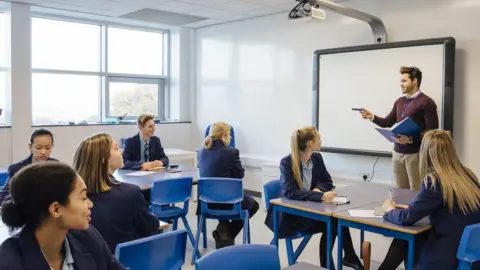 Getty Images A teacher stands in front of a white board in a classroom