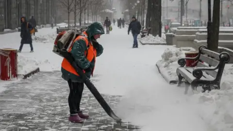 Reuters A municipal worker removes snow in central Kyiv