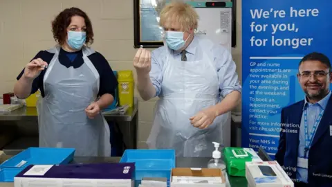 PA Media Prime Minister Boris Johnson is shown how to prepare the vaccine by advance nurse practitioner Sarah Sowden in Batley.