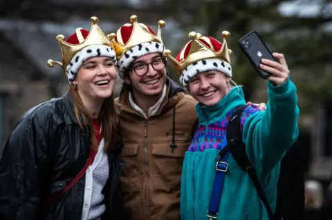 Getty Images Members of the public pose wearing crown-styled hats