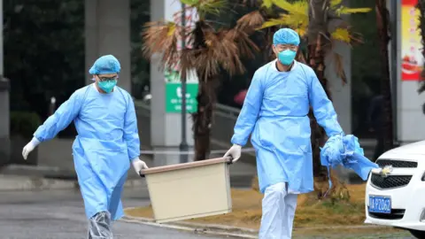 Reuters Medical staff carry a box as they walk at the Jinyintan hospital, where the patients with pneumonia caused by the new strain of coronavirus are being treated, in Wuhan