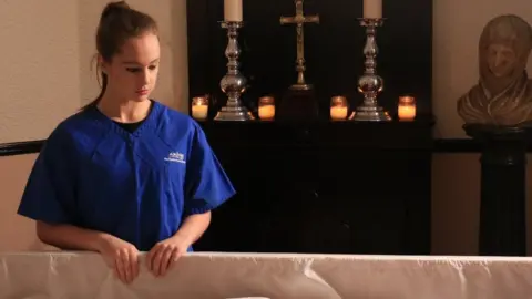 BBC Ellie stares at an open coffin