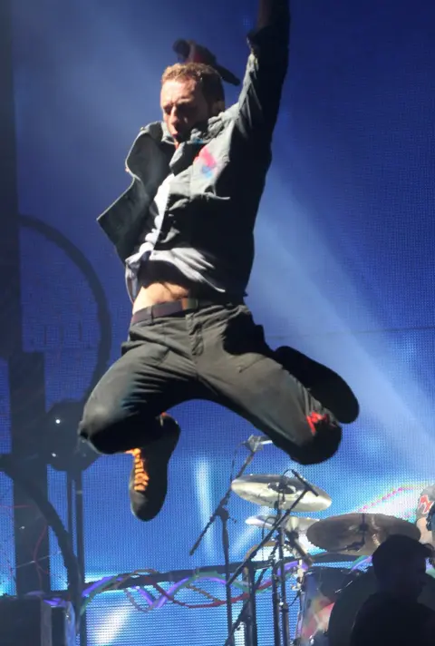 Dave J Hogan / Getty Images  Chris Martin from Coldplay jumps into the air while on stage