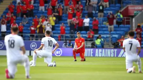 PA Media Wales's Chris Mepham takes a knee