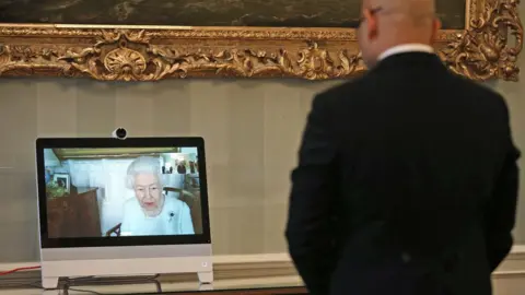 PA Media The Queen appears on a screen by videolink from Windsor Castle during a virtual audience to receive Gil da Costa, Ambassador of Timor-Lest