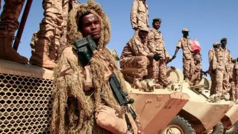 Getty Images Sudanese soldiers stand next to their vehicles during a military exercise in the Maaqil area in the northern Nile River State, on December 8, 2021