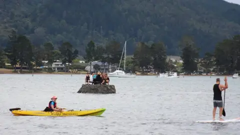 David Saunders New Year revellers enjoy a drink on a special sand island they constructed earlier in the Tairua estuary on the Coromandel peninsula