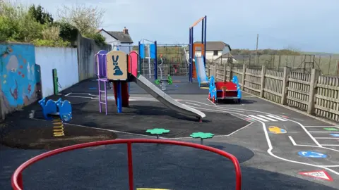 Torridge District Council Northgate play area with new equipment including a climbing frame with a slide, a spring seat and patterns on the floor.