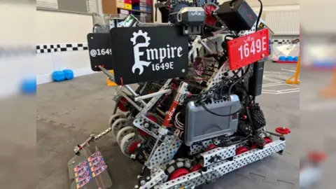 The hand-built robot has 'Empire' branded on the side of it. It is made up on a combination of wire, metal parts and wheels. 