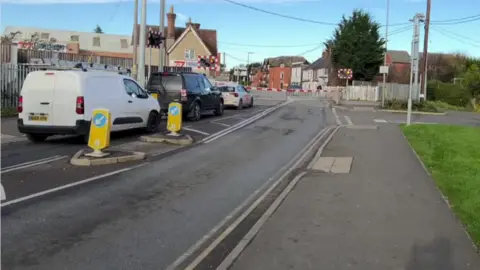 BBC Two cars and a van queue at the London Road level crossing in Bicester. 