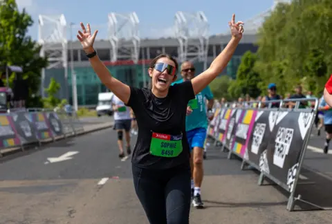 Great Manchester Run A female runner in black T-shirt and black leggings runs away from Old Traffrod home of Manchester United FC.