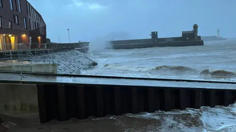 A wave hitting a stone sea wall.