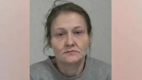 Police custody image of Donna English. She is looking directly into the camera, and has dark hair. She is wearing a grey sweatshirt.
