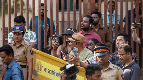 Hindustan Times via Getty Images People standing near a police barricade with their phones, as police stand nearby 