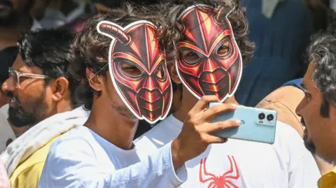 Two young male supporters of India's Cockroach Janta Party wearing cockroach masks and taking selfies during the cockroach protests in June 2026