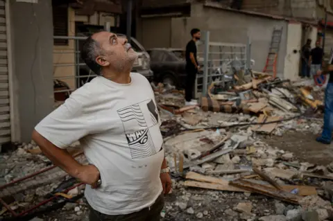 Joel Gunter/BBC Musa Araf, looks up at his damaged building, which shook violently when the missile hit.