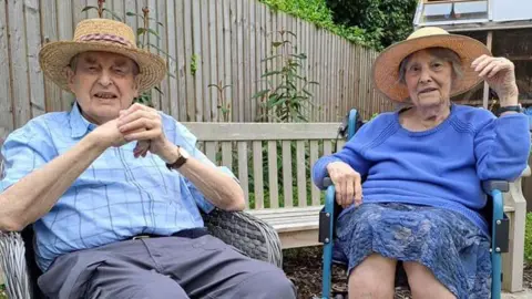 Middleton Lodge Peter and Eileen sit outside with straw sun hats on.